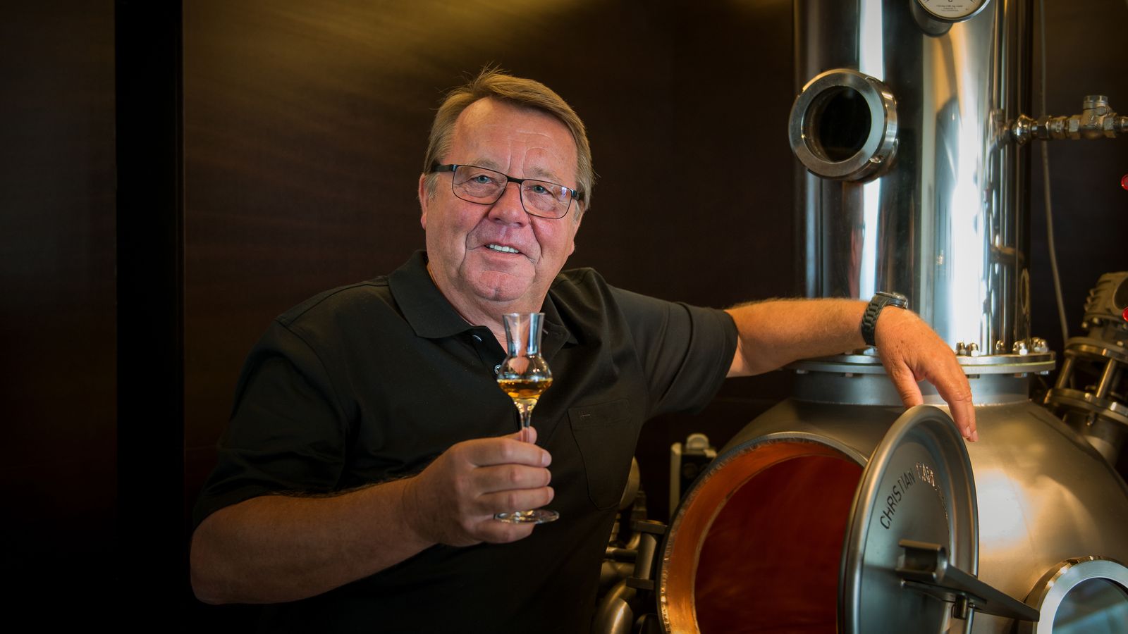 Manfred Wöhrer mit einem Glas Edelbrand an seiner Brennanlage